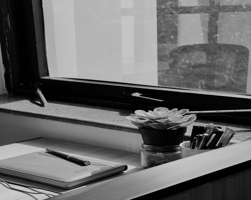 A clean workspace desk beside a window showing an organized notebook and water glass